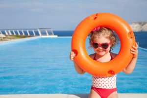 little girl in swimsuit takes lifebuoys backgraund swimming pool